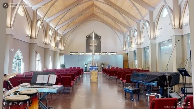 A church with red chairs and a cross on the wall.