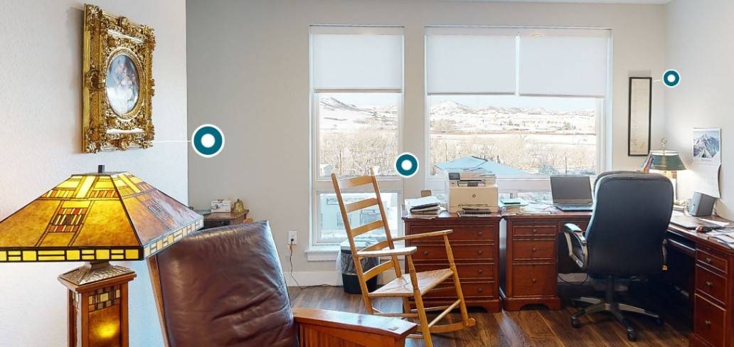 A living room with two windows and a rocking chair.